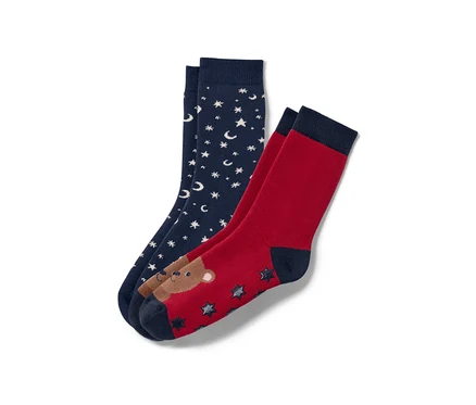 Zwei Paar Kinder-Antirutsch-Socken: ein Paar dunkelblau mit weißen Sternen und Monden, ein Paar rot mit Bär und Sternen.