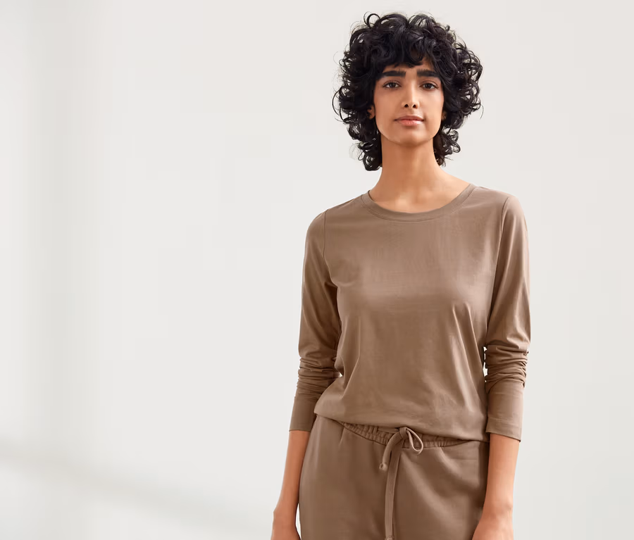 Frau trägt NAH/STUDIO Jogginghose und Longsleeve aus nachhaltiger Baumwolle in Hazelnut.