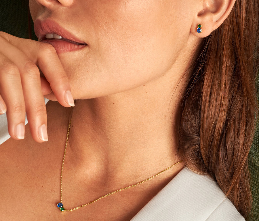 Detail einer Frau mit Finger am Mund, die eine blaugrüne 925 Silber Kette und blaugrüne 925 Silber Ohrstecker trägt.