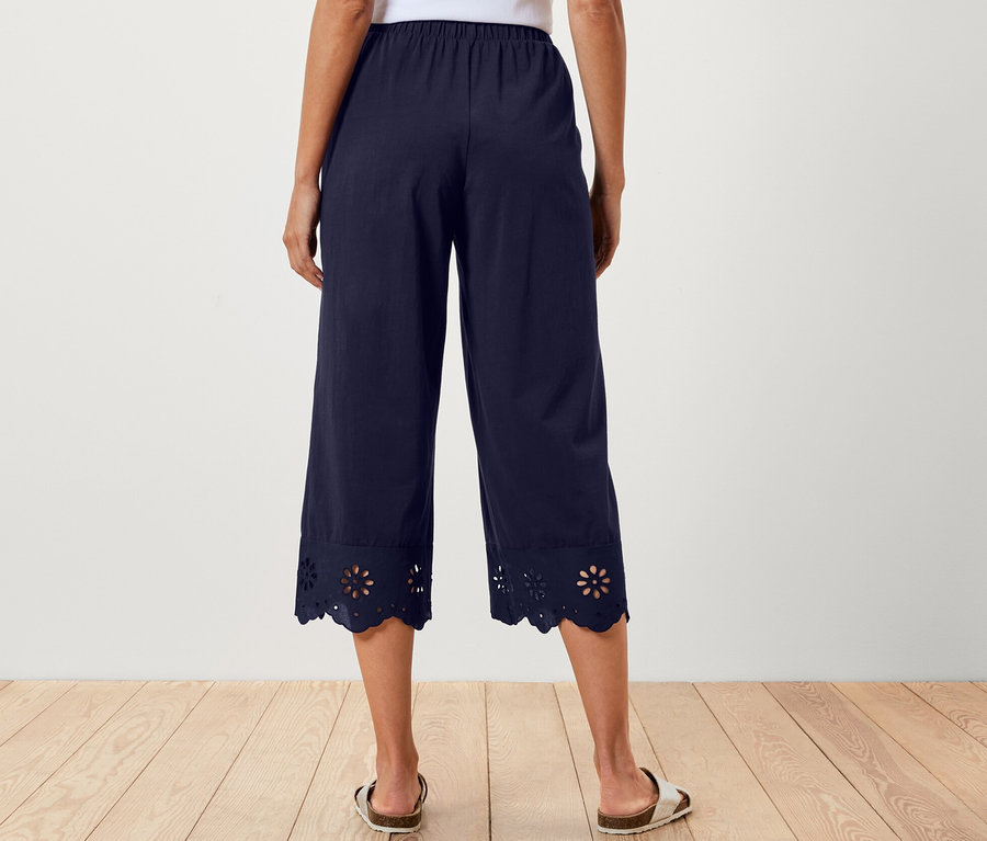 Frau von hinten in weißem Top und dunkelblauer Culotte mit Stickerei am Saum.