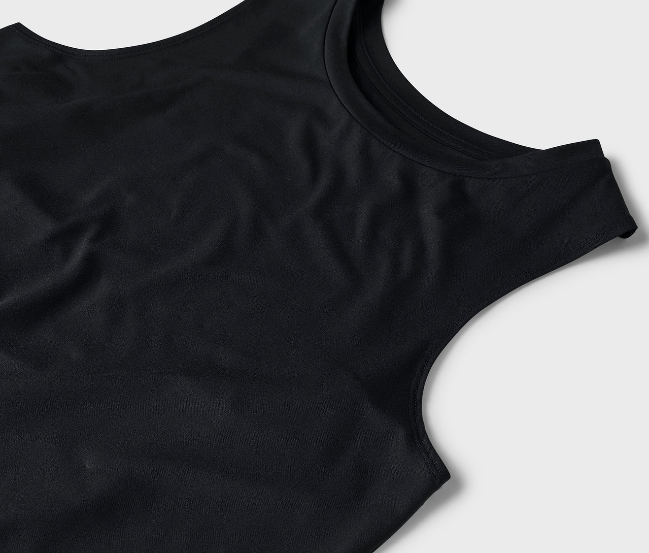 Detailaufnahme eines schwarzen Tanktops auf grauem Hintergrund.