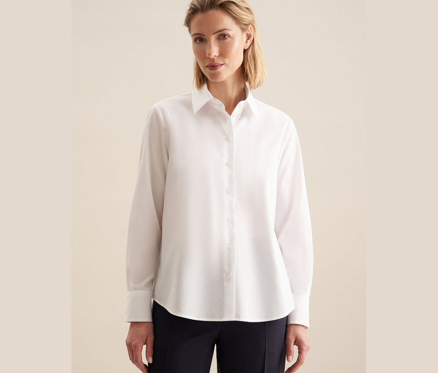 Frau trägt eine weiße, bügelfreie Seidensticker Bluse.