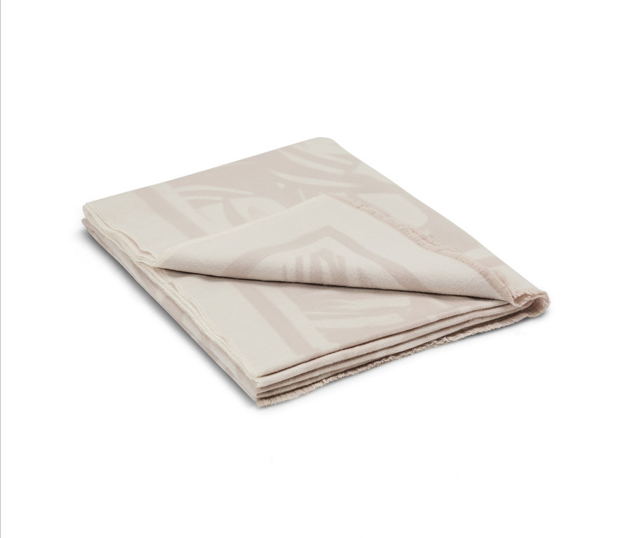 Gefaltete beige Decke mit geometrischem Muster.