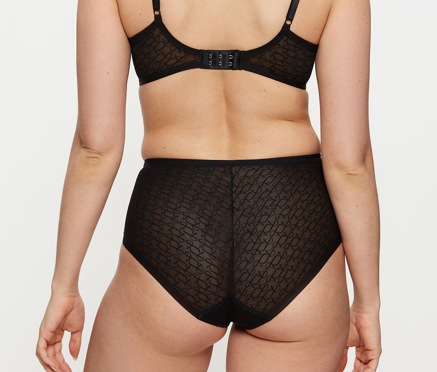 Rückansicht einer Frau, die einen schwarzen BH und einen schwarzen Triumph Signature Sheer Maxi EX Slip trägt.