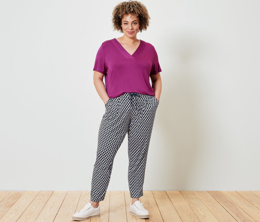 Frau posiert in einem Shirt mit Faltendetail, berry, und einer bedruckten Jerseyhose.