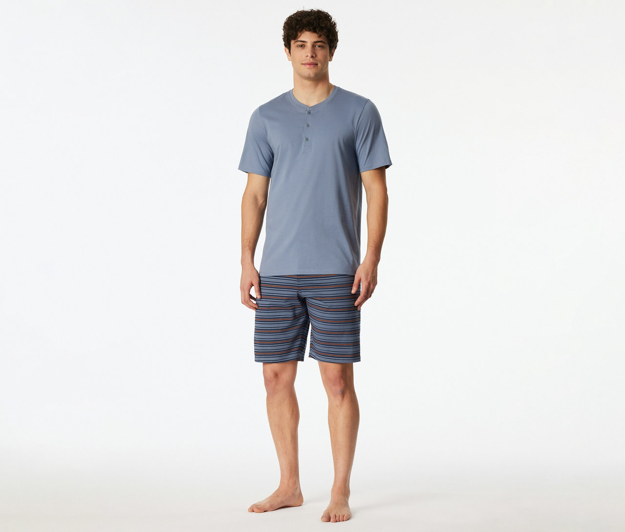 Mann trägt ein blau-graues SCHIESSER Shorty-Set mit kurzärmeligem Henley-Oberteil und gestreiften Shorts.