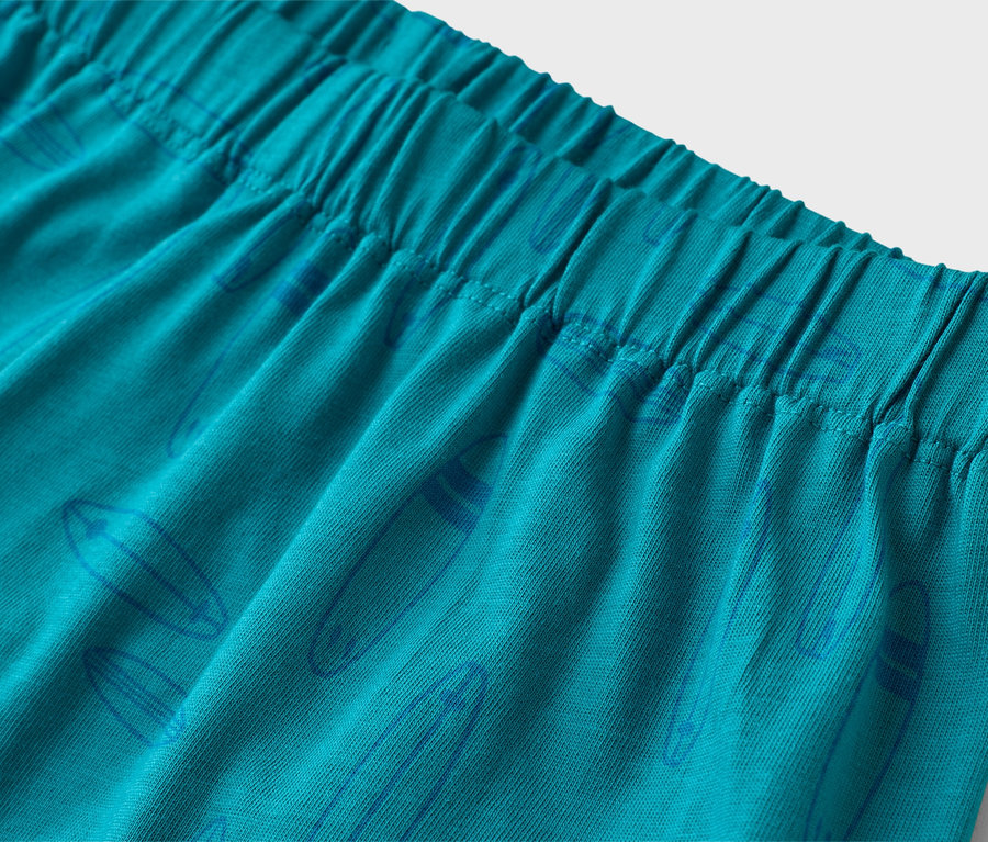 Nahaufnahme von türkisfarbenen Shorts mit elastischem Bund und blauem Surfbrettmuster.