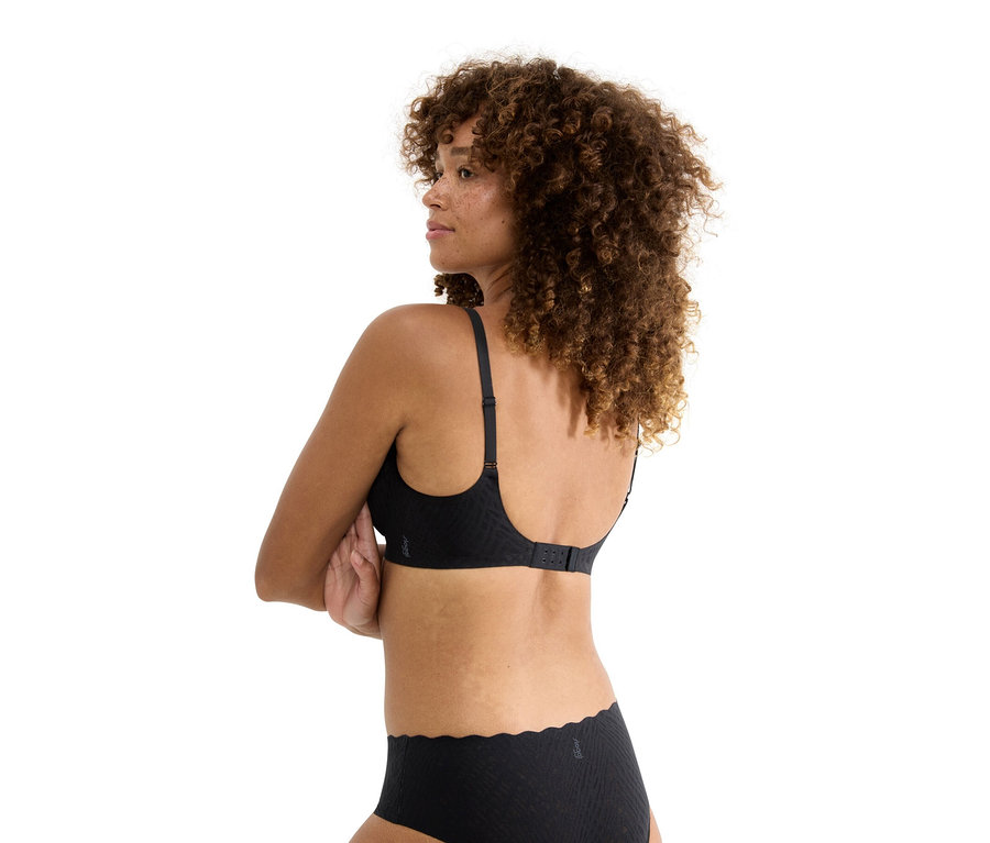 Frau mit lockigem Haar, von hinten gesehen, trägt schwarzen BH und passende Unterhose.