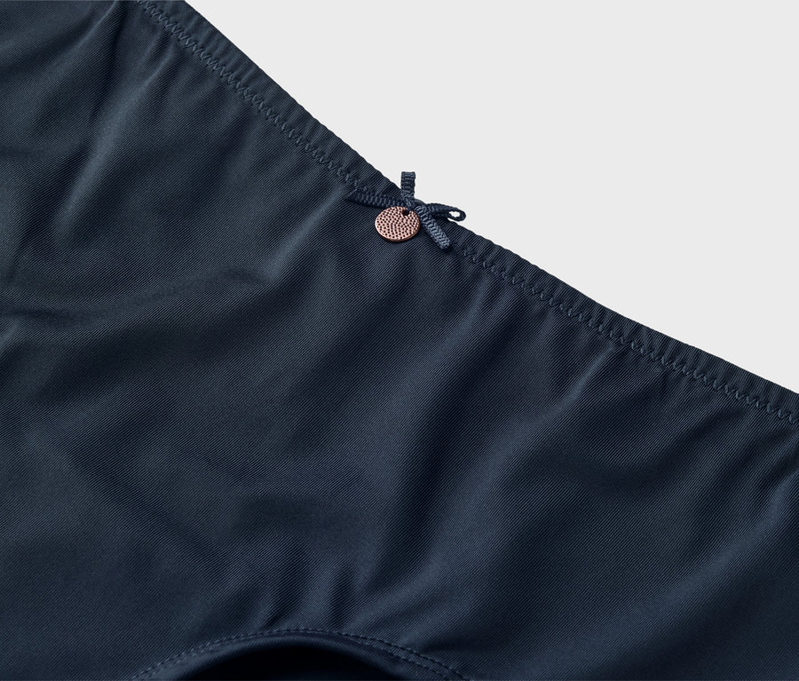 Detailaufnahme von dunkelblauer Unterwäsche mit Schleife und kleinem Knopf.