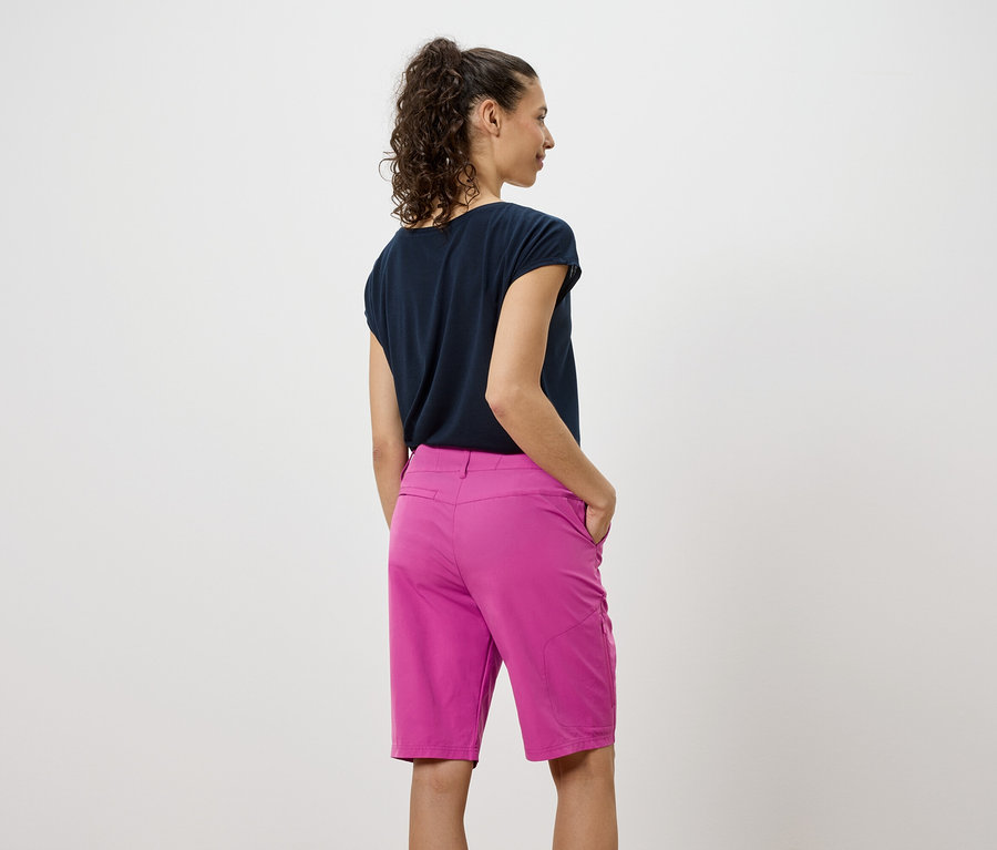 Rückansicht einer Frau mit dunklem Shirt und pinken Shorts.