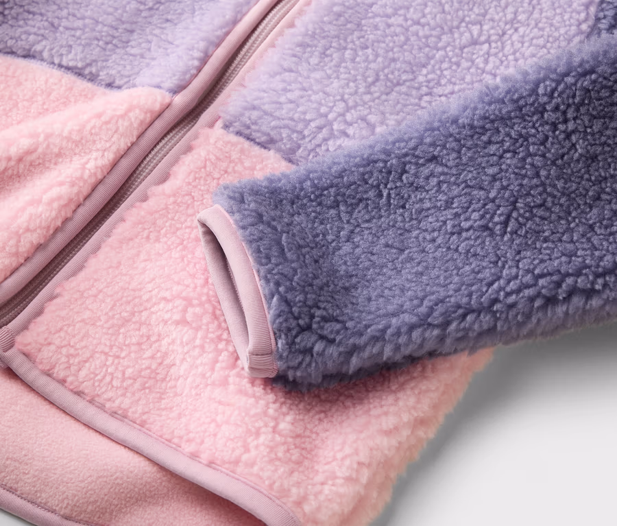 Nahaufnahme einer Fleecejacke mit Reißverschluss in Rosa, Lila und Dunkellila.
