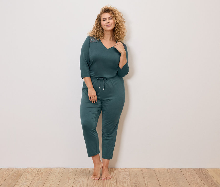 Frau mit lockigem Haar, die einen marineblauen Pyjama mit langen Ärmeln und einer Kordel an der Taille trägt.