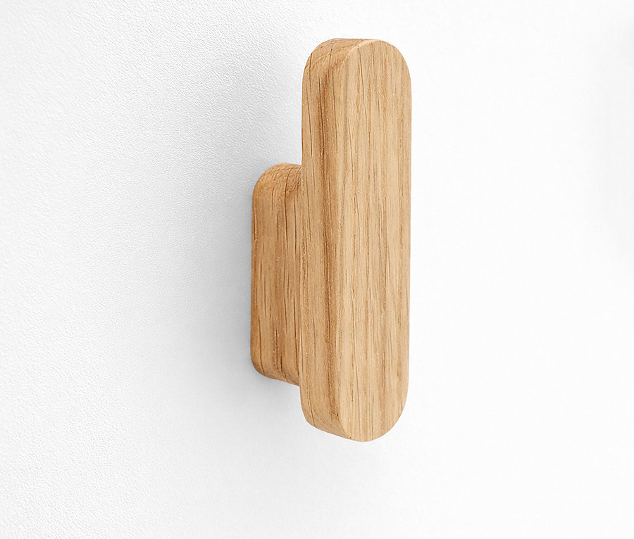 Nahaufnahme eines einzelnen hölzernen Wandhakens an einer weißen Wand.