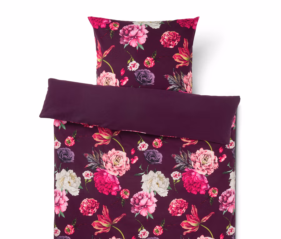 Dunkelviolette Bettwäsche mit Blumenmuster, bestehend aus einem Kissen und einem gefalteten Bettbezug mit rosa, fuchsiafarbenen und weißen Pfingstrosen.