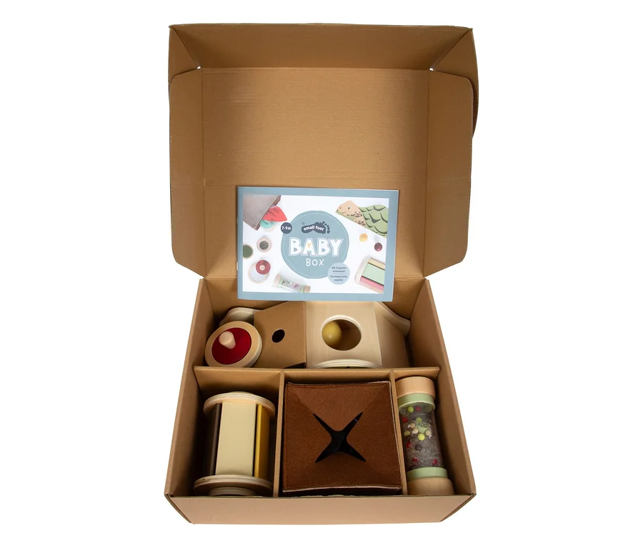 Offene small foot Baby-Box, 7–9 Monate, mit Holzzug, Haus, Zylinder, Filzwürfel und Rassel gefüllt.