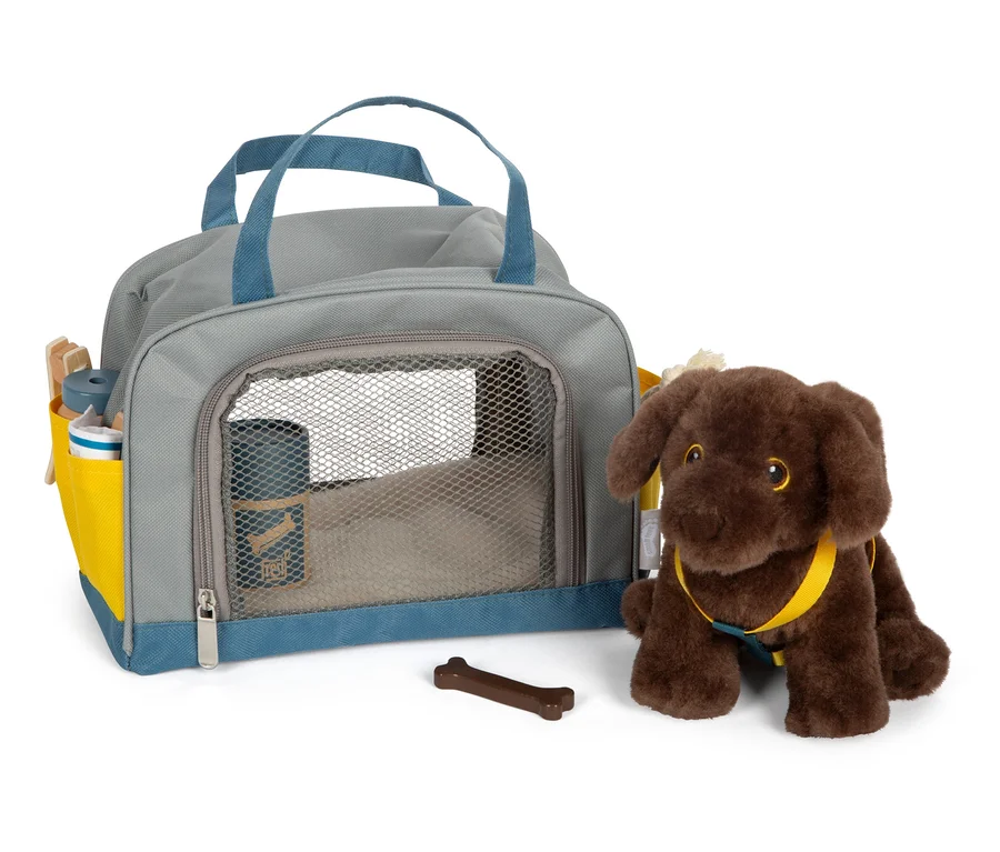 Ein brauner Plüschhund sitzt neben einer grauen Tasche mit blauen Details und einem braunen Knochen.