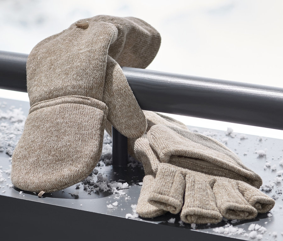 Beige Strickfleece-Klappfäustlinge liegen auf einer verschneiten Oberfläche.