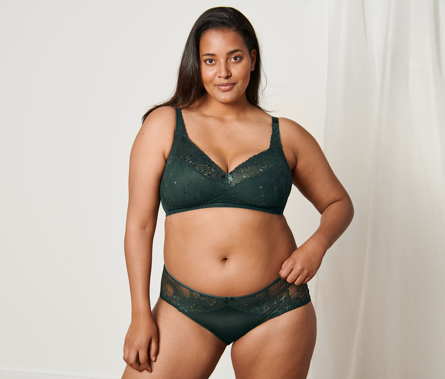 Frau posiert in einem grünen Dessous-Set, bestehend aus Soft-BH und Midrise-Panty.