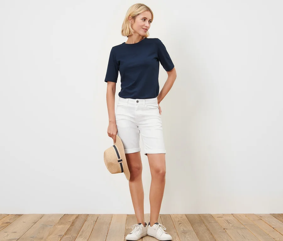 Frau steht mit Hut in der Hand und trägt eine Bermuda Colored Jeans – Fit »Lea«.