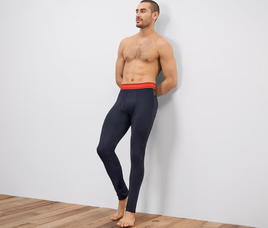 Mann lehnt an Wand und trägt eine Thermo-Funktionsunterhose.