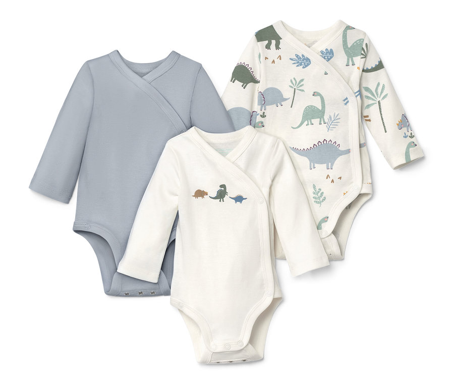 Drei Langarmbodys, einer blau, einer mit Dino-Motiv, einer mit Dino- und Pflanzenmuster.