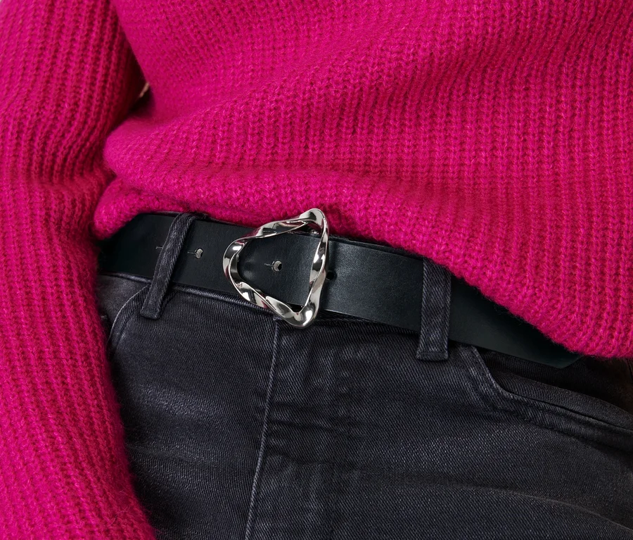 Schwarzer Ledergürtel mit dekorativer Silberschnalle an einer Jeanshose.