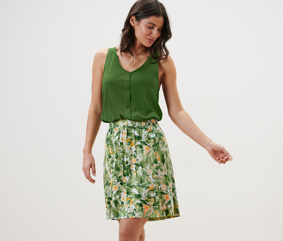 Frau trägt ein grünes Top und einen bedruckten Jerseyrock.
