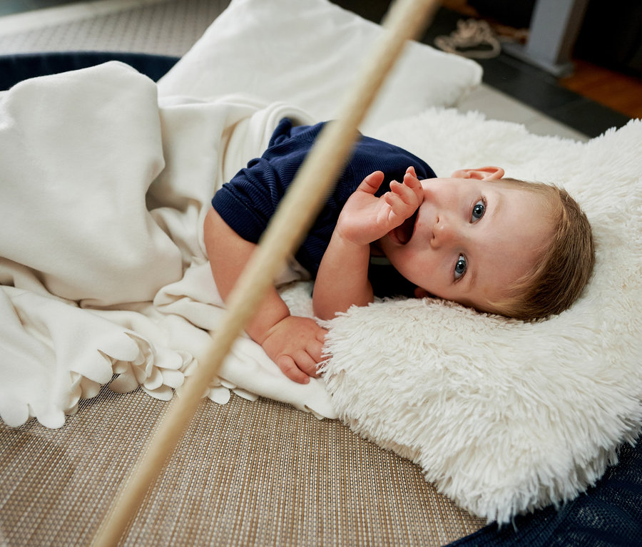 Ein Baby liegt in einer HUDORA Nestschaukel »Lounge«, midnight, Ø 110 cm und HUDORA Nestschaukel »Lounge«, midnight, Ø 90 cm, zugedeckt mit einer Decke.