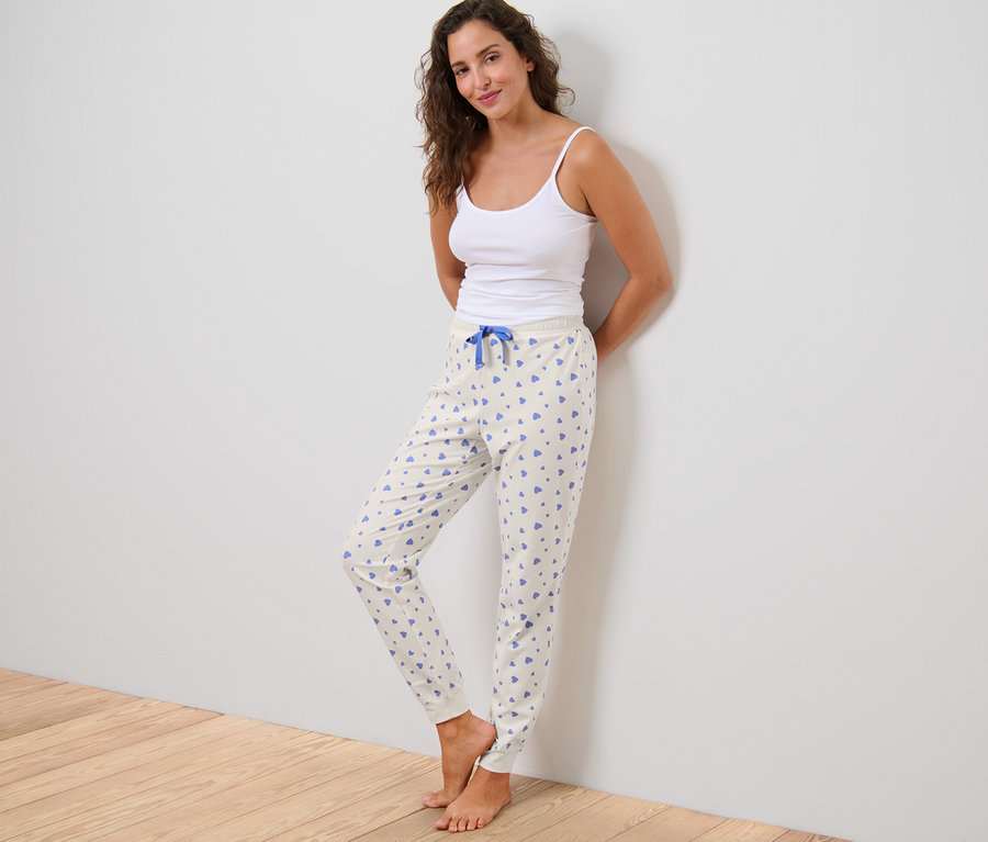 Frau im Tanktop posiert in Pyjamahose mit Herzen.