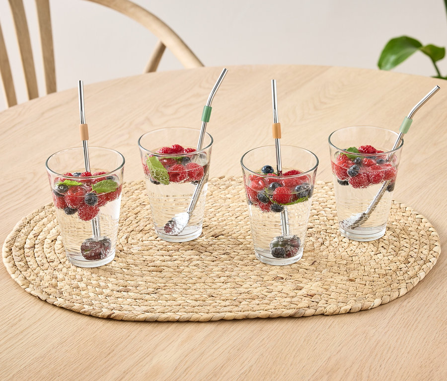 Vier Gläser mit Wasser, Früchten und 4 Löffel auf einem Tisch.