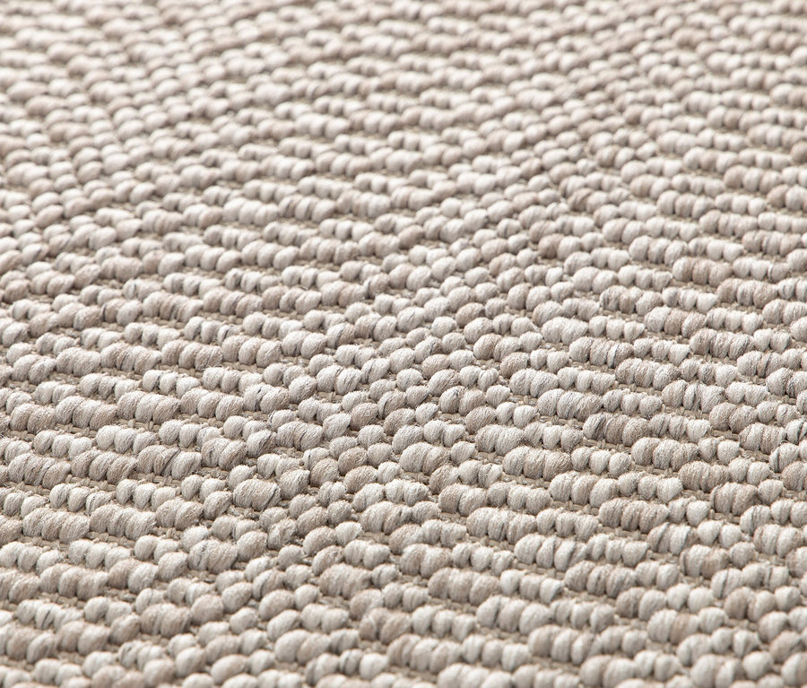 Nahaufnahme eines beigen Teppichs »Twine« mit natürlicher Struktur.