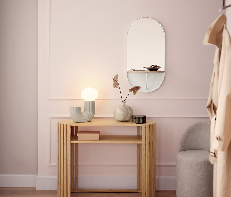 Heller Flur mit einem hölzernen Konsolentisch, einer Lampe, einem Spiegel und einem grauen Hocker.
