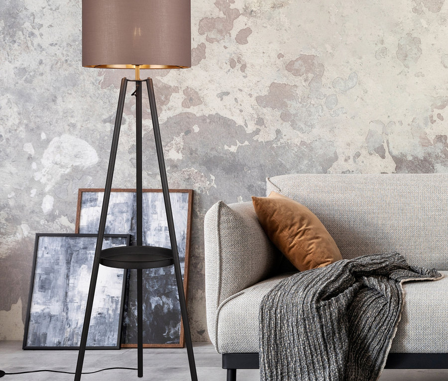 Stehlampe mit braunem Schirm neben Sofa mit braunem Kissen und grauer Decke.