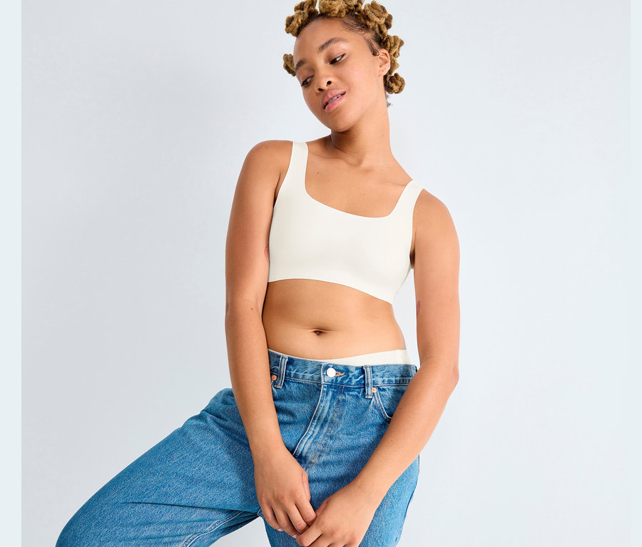 Junge Frau posiert in Jeanshose und Sloggi ZERO Feel 2.0 Top in Seidenweiß.