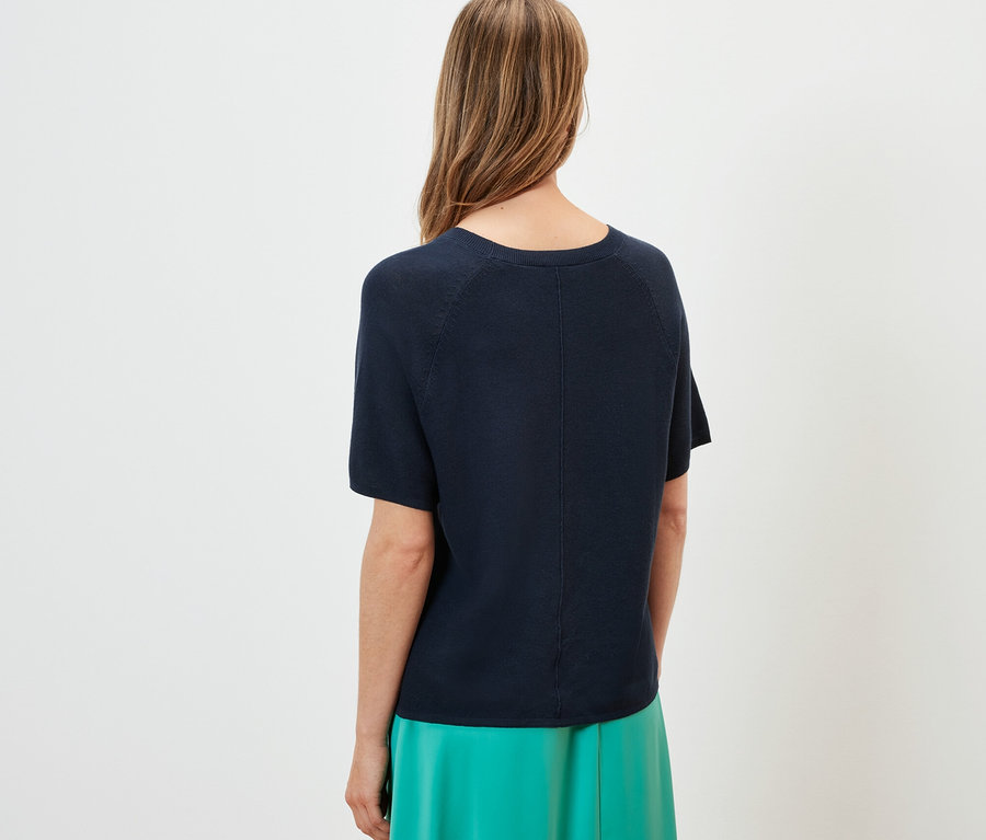 Rückansicht einer Frau mit navy Feinstrick-Shirt und grünem Rock.