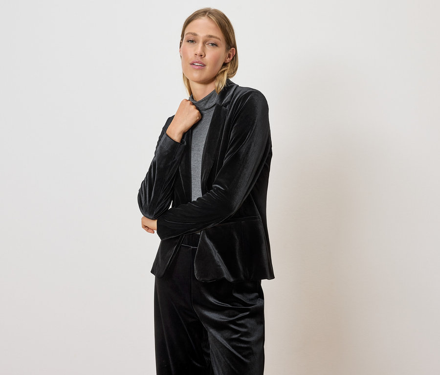 Frau posiert in schwarzem Samt-Blazer und Hose.