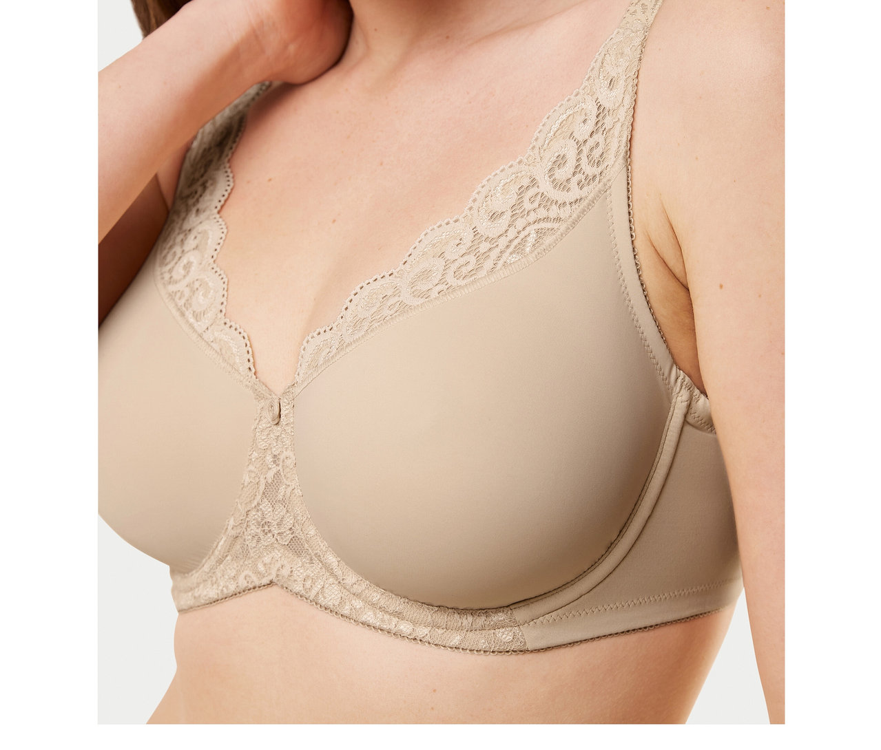 Frau trägt einen hautfarbenen Triumph Amourette Minimizer-BH mit Spitzendetails am oberen Rand und zwischen den Cups.