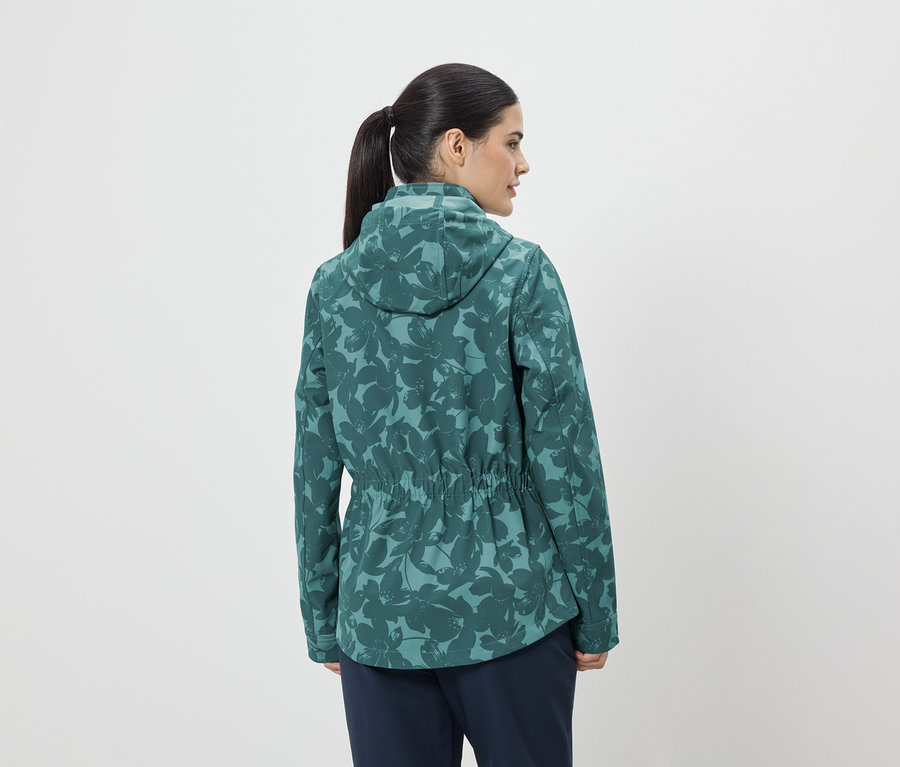 Frau von hinten, mit Pferdeschwanz, trägt eine grüne, blumengemusterte Jacke mit Kapuze und Kordelzug.