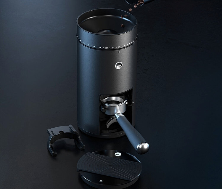 Eine schwarze Kaffeemühle mit Bohnen im Trichter, einem Siebträger und einer Waage auf einem dunklen Tisch.