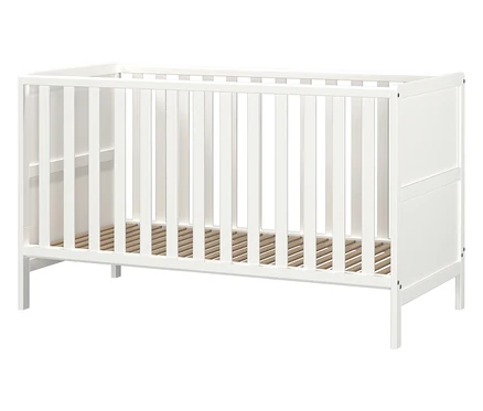 Weißes Kinderbett mit Holzlattenrost vor neutralem Hintergrund.