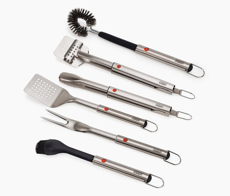 Sechs silberne Grillwerkzeuge liegen auf einem weißen Hintergrund.