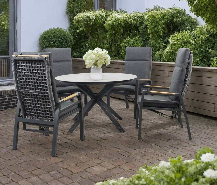 Grauer deVries Tisch (Ø ca. 120 cm) mit vier Stühlen auf einer Terrasse.