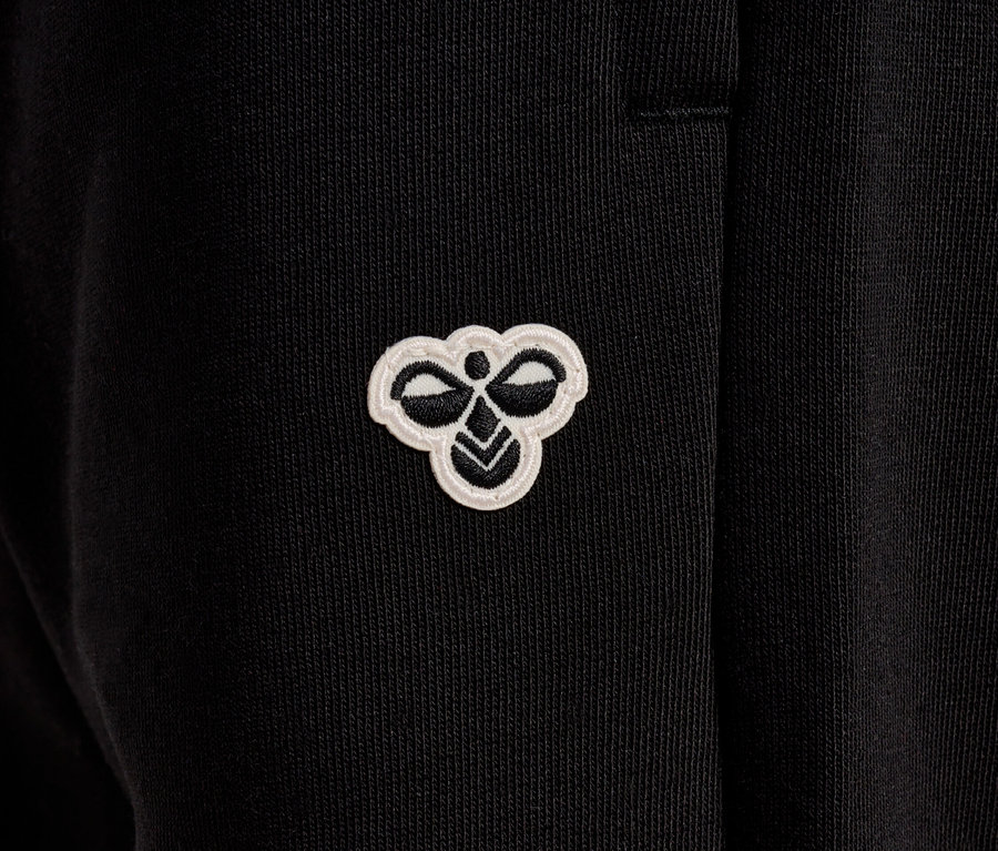 Nahaufnahme einer schwarzen Hose mit einem kleinen, weißen Hummel-Logo.