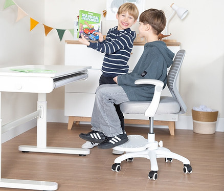 Zwei Jungen. Einer zeigt ein Buch, der andere sitzt auf dem Roba Kinderschreibtisch mit Kinderbürostuhl Set in Weiß-Grau.