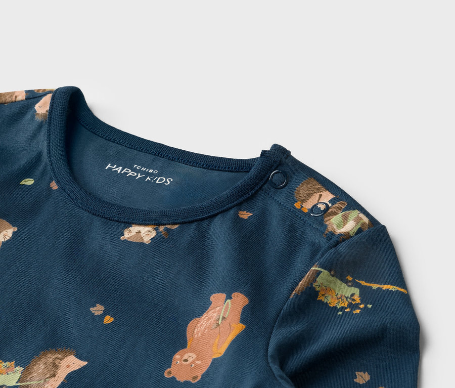 Detailansicht eines dunkelblauen T-Shirts mit Tiermuster und zwei Knöpfen an der Schulter.