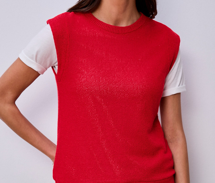 Frau mit Street One Shirt unter roter Strickweste und Jeans. Sie hat die Hand in der Hosentasche.