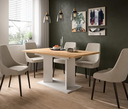 Ein modernes Esszimmer mit einem Holztisch und sechs beigen Stühlen. Auf dem Tisch stehen eine Obstschale, Kerzen, Teller und Gläser. Eine dunkelgrüne Wand mit drei Bildern und drei Pendelleuchten ist im Hintergrund zu sehen.