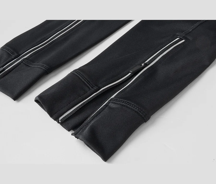 Nahaufnahme des unteren Teils einer schwarzen Hose, die weiße Streifen und Reißverschlüsse an den Knöcheln zeigt.