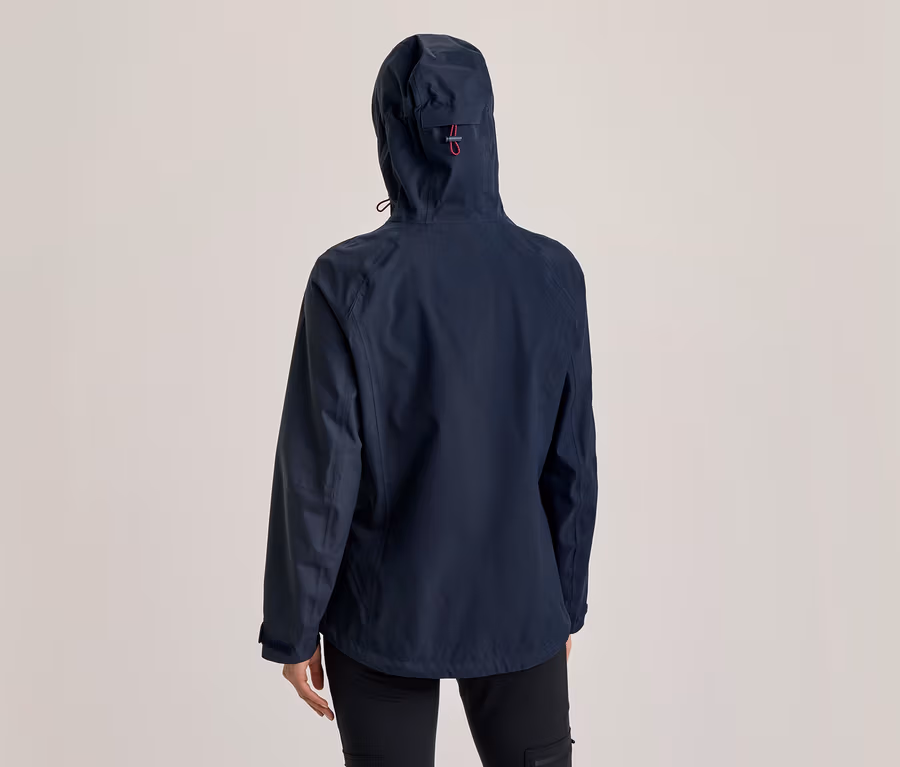 Person von hinten in einer dunkelblauen Kapuzenjacke mit rotem Detail an der Kapuze und schwarzer Hose.