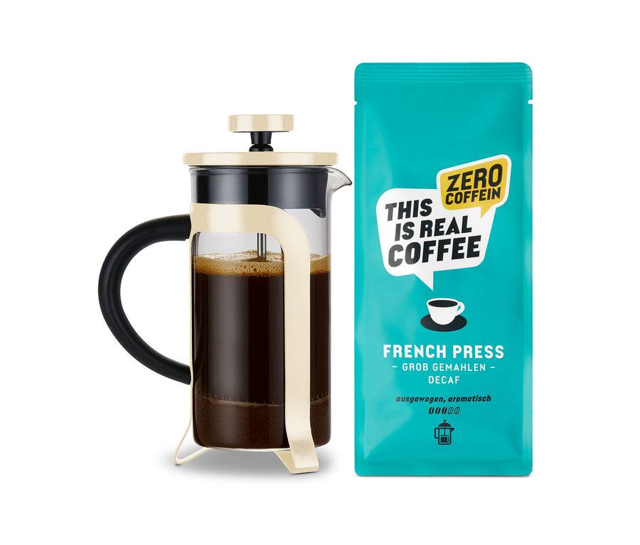 Eine French Press Kaffeekanne mit Kaffee neben einer türkisfarbenen Kaffeepackung.